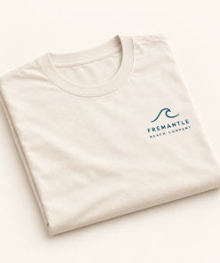 Folded cream Coastal Wave Tee with navy wave and Fremantle Beach Company chest artwork